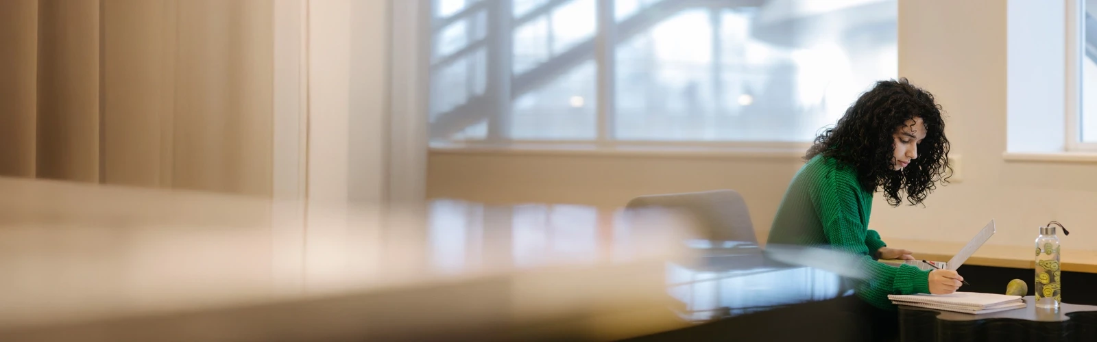 Studenten Sarah pluggar med dator och anteckningsblock.