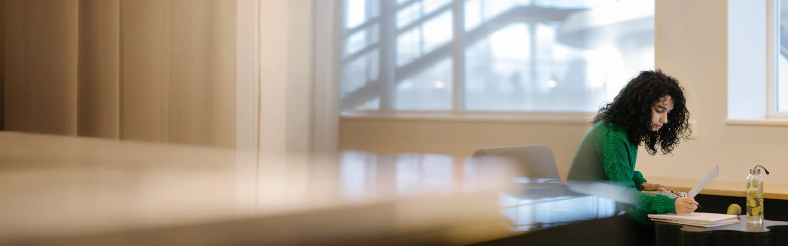 Studenten Sarah pluggar med dator och anteckningsblock.