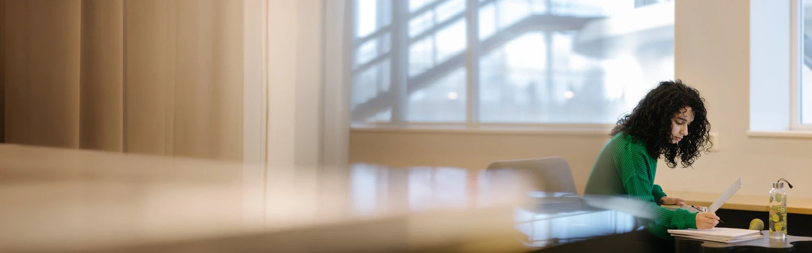 Studenten Sarah pluggar med dator och anteckningsblock.