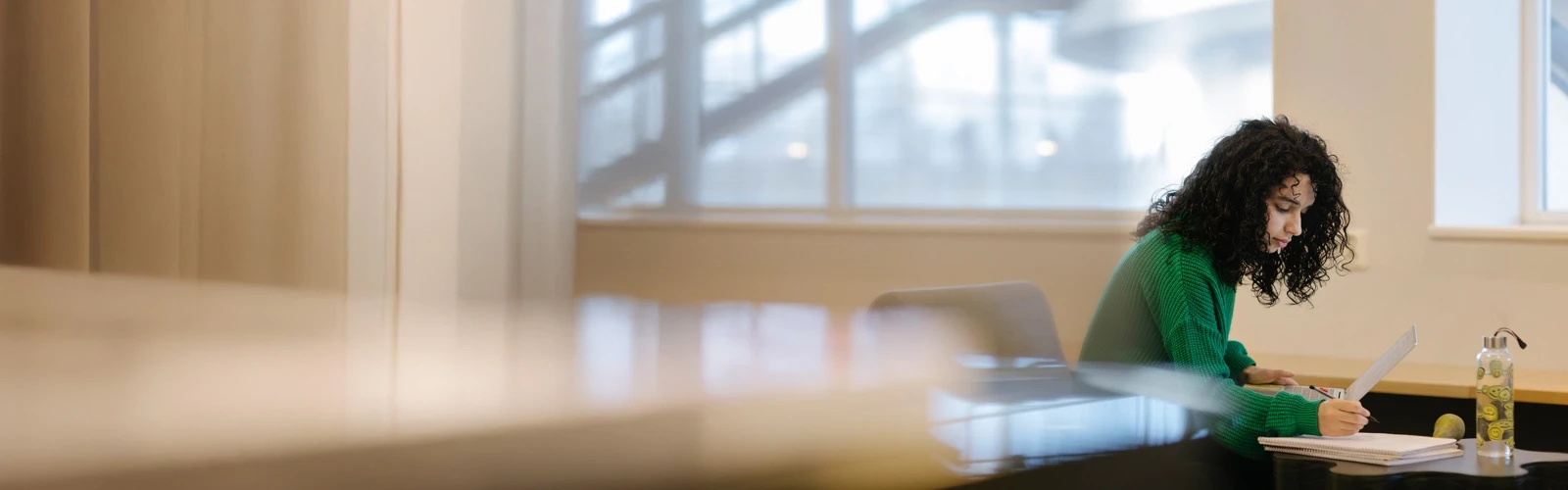 Studenten Sarah pluggar med dator och anteckningsblock.