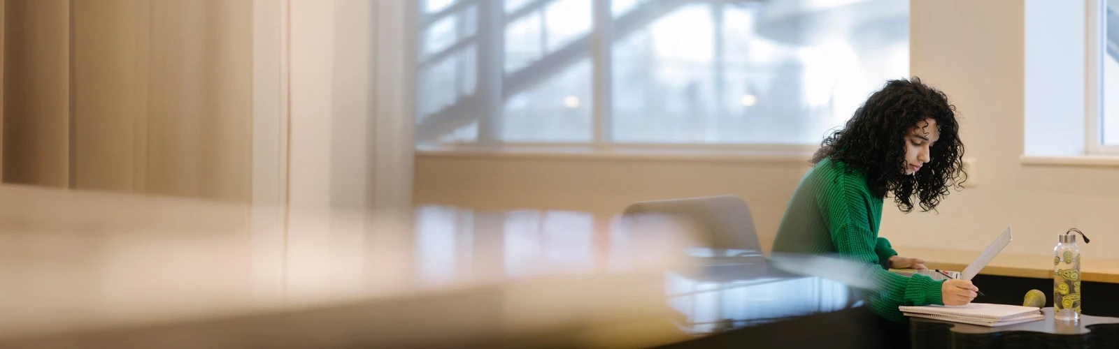 Studenten Sarah pluggar med dator och anteckningsblock.