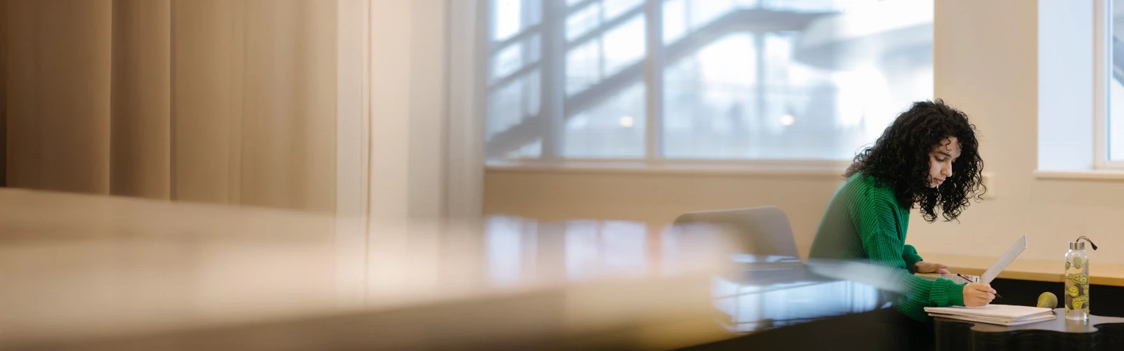 Studenten Sarah pluggar med dator och anteckningsblock.