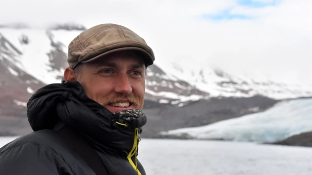 Portrait photo of Viktor Gydemo, snowy mountains and lake in the background