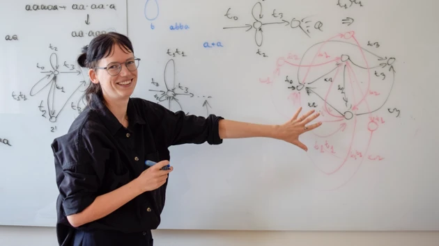 Bild på Willeke Martens vid whiteboardtavla med figurer och formler