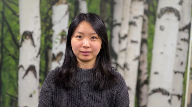 En kvinna står framför en målning med träd