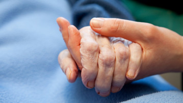 Detalj på en ung hand som håller en gammal hand i sin.