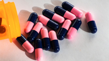 Närbild på rosa och blå antibiotikatabletter.