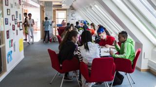 En grupp skolelever på högstadiet sitter vid ett bord och äter mat.