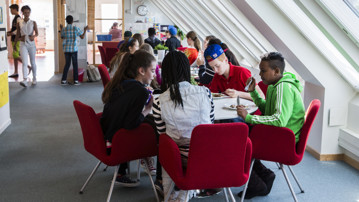 En grupp skolelever på högstadiet sitter vid ett bord och äter mat.