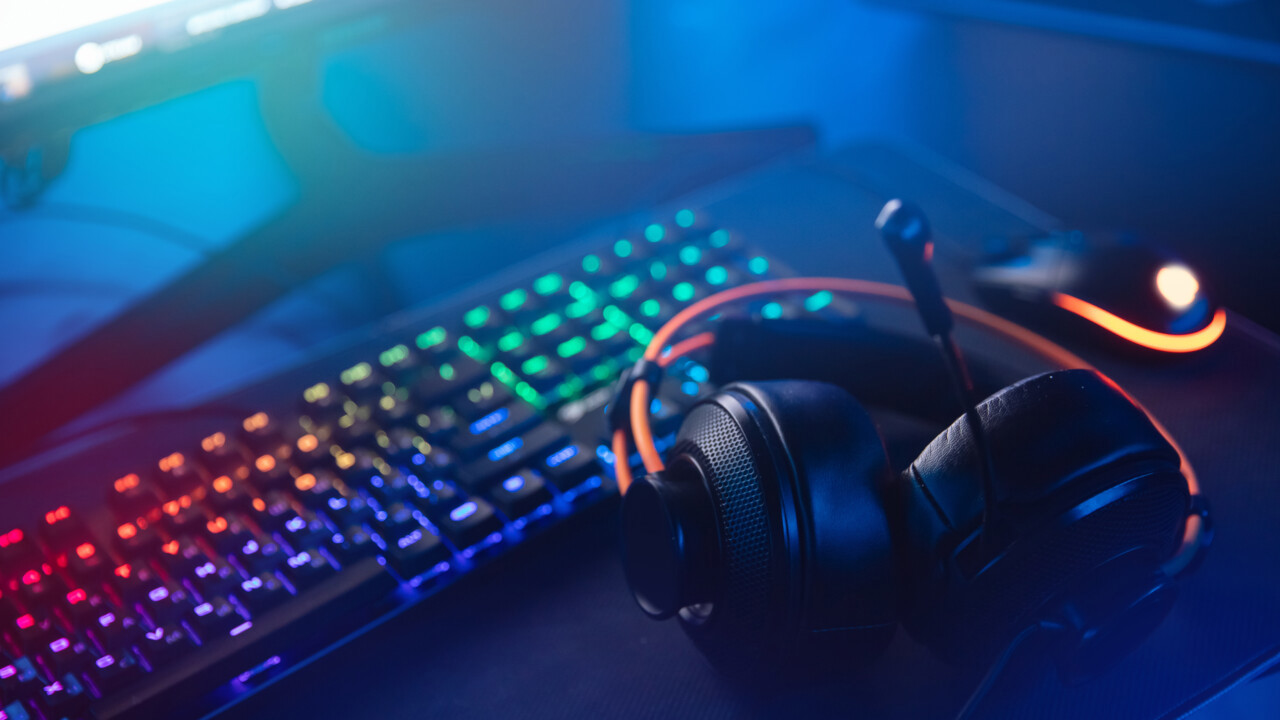 Bilden visar ett tangentbord med lysande tangenter och ett headset, med blå bakgrund.