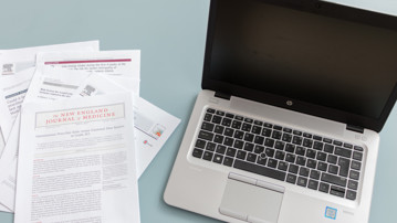 Vetenskapliga artiklar bredvid bärbar dator