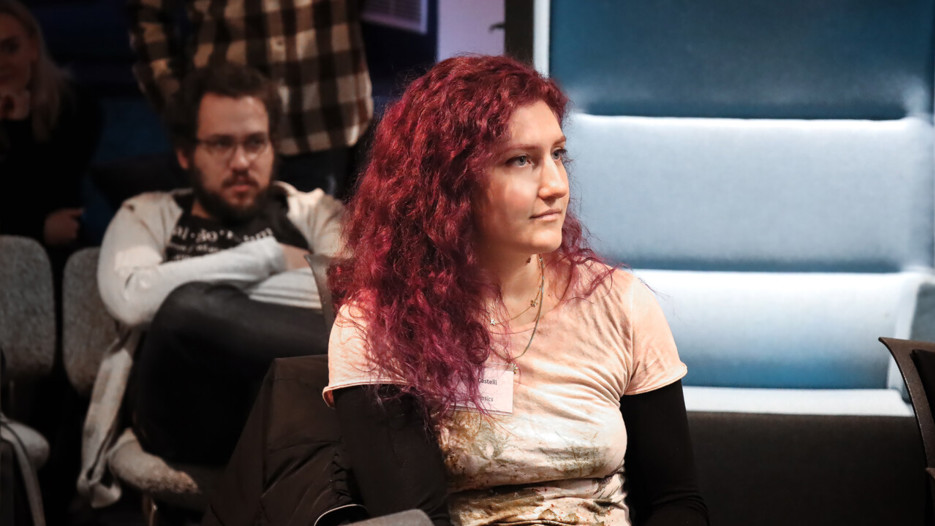 Bilden visar en kvinnlig student med rosa hår som tittar bort från kameran.