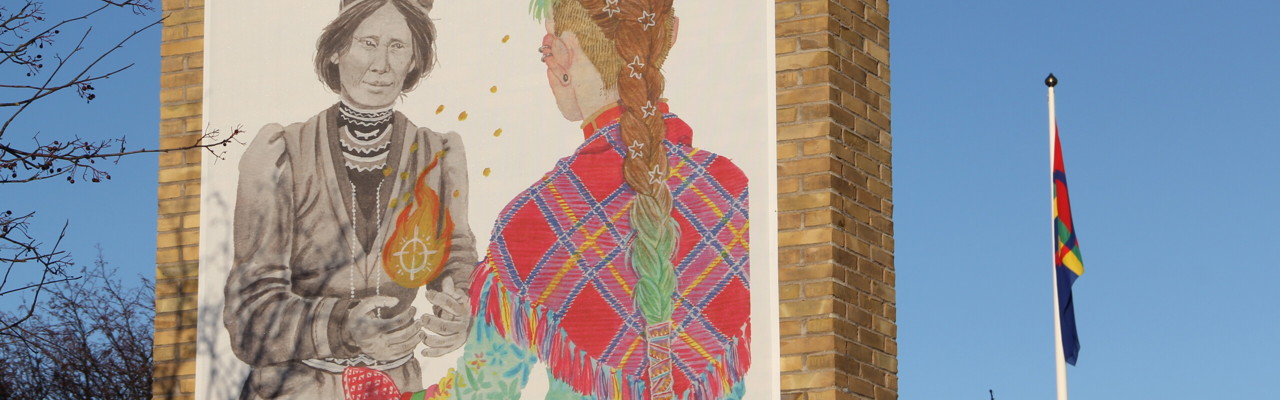 Foto på vepa föreställandes Elsa Laula som sträcker över en flammande låga till ung, samtida same