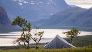 Tält i Sarek med sjö och fjäll i bakgrunden.