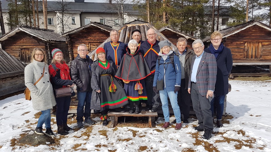 Deltagare i seminarium står samlade framför skogsamiska kåtor