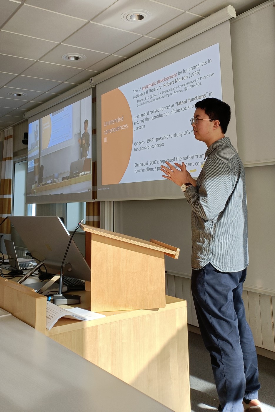 Yue Wang stands in front of a powerpoint